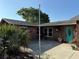Welcoming front of a brown home featuring a turquoise door, neat landscaping, and a concrete patio at 11314 Huggins St, Leesburg, FL 34788