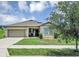 Charming single-story home with a well-manicured lawn, attached garage, and inviting entrance at 16406 Blooming Cherry Dr, Groveland, FL 34736