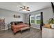 Cozy main bedroom with wood floors, large windows, ceiling fan, and stylish decor at 16406 Blooming Cherry Dr, Groveland, FL 34736
