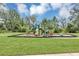 Community playground with lush grass, mature trees, and blue sky at 16406 Blooming Cherry Dr, Groveland, FL 34736