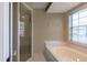 Bright bathroom featuring a glass door shower and a soaking tub under a window at 1947 Broadleaf Ct, Windermere, FL 34786