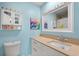 Light blue bathroom featuring a white vanity, framed mirror, and cabinet at 214 Majors Ln # C, Kissimmee, FL 34743
