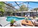 Inviting in-ground screened pool with comfortable seating, surrounding trees, and a clear blue sky at 2420 Kerridale St, Deltona, FL 32738