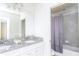 Bathroom with granite counters, double sinks, tiled floors, and shower with lavender curtain at 2439 Dubai St, Kissimmee, FL 34747