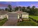 Charming single-story home with a brick driveway, two-car garage and beautiful evening sky at 2479 Pine Preserve Ct, St Cloud, FL 34771