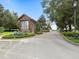 Close-up of a gated entrance featuring stone accents, mature trees, and manicured flower beds at 267 Osprey Hammock Trl, Sanford, FL 32771