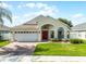 Charming single-story home with a red front door, manicured lawn, and brick paved driveway at 2729 Stanwood Dr, Kissimmee, FL 34743