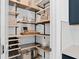 Open walk-in pantry with wood shelving, black metal brackets, baskets, and space for storing kitchen appliances at 3324 Orange Rose Loop, Apopka, FL 32712