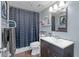 Bathroom with a dark patterned shower curtain, floating shelves, mirror and wood look flooring at 400 E Colonial Dr # 207, Orlando, FL 32803
