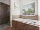 Relaxing bathroom with a soaking tub, tiled surround, and separate tiled shower at 4065 Shadowind Way, Gotha, FL 34734