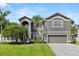 Beautiful two-story gray home with lush landscaping, manicured lawn, and a paved driveway at 4065 Shadowind Way, Gotha, FL 34734
