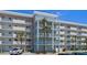 Exterior building view showing multiple floors, balconies, palm trees, and parking at 4153 S Atlantic Ave # 2120, New Smyrna Beach, FL 32169