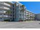 A multi-story condominium with a light blue exterior and ample parking spaces for residents and visitors at 4153 S Atlantic Ave # 2120, New Smyrna Beach, FL 32169