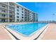 Community pool with blue water, brick perimeter, chairs, and view of the beachside building at 4153 S Atlantic Ave # 2120, New Smyrna Beach, FL 32169