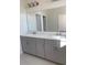 This bathroom features a double vanity, a large mirror and grey cabinetry at 605 Big Pine Ave, Minneola, FL 34715