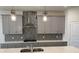 Close up of kitchen featuring gray cabinetry, quartz countertop, designer backsplash and stainless steel vent at 605 Big Pine Ave, Minneola, FL 34715