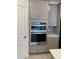 Modern kitchen featuring stainless steel double ovens and gray cabinetry and stylish backsplash at 605 Big Pine Ave, Minneola, FL 34715