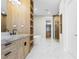 Bright bathroom with double vanity, marble counters, a free-standing tub, open shelving, and marble flooring at 7706 Ficquette Rd, Windermere, FL 34786