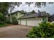Back exterior with a multi-car garage, set on a large driveway, with mature landscaping for privacy at 8335 Lake Burden Circle, Windermere, FL 34786