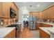 Well-lit kitchen featuring wooden cabinetry, stainless steel appliances, and a charming diamond-patterned tile backsplash at 8335 Lake Burden Circle, Windermere, FL 34786