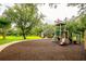 Community playground featuring slides, swings, and a covered picnic area amidst mature trees at 8335 Lake Burden Circle, Windermere, FL 34786