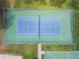 Aerial view of a vibrant blue and green tennis court enclosed by green fencing and lush grass at 848 Magnolia Creek Cir, Orlando, FL 32828