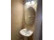 Cozy powder room featuring a pedestal sink, an oval mirror, and a three-light vanity fixture at 8608 Falstaff Pl, Oviedo, FL 32765