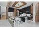 Bright, modern kitchen with marble island with seating, black cabinets, wood accents, and stainless steel appliances at 9259 Tibet Pointe Cir, Windermere, FL 34786