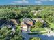 Aerial view of a brick home with a well-manicured lawn surrounded by mature trees and a lake view at 9455 Belmont Ter, Oviedo, FL 32765