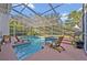 Screened in pool area with blue tiled pool, spa, wood lounge chairs, and manicured lawn at 9455 Belmont Ter, Oviedo, FL 32765