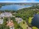 An aerial shows an estate home by a lake, pool, trees, and a neighborhood under construction at 1112 Preserve Point Dr, Winter Park, FL 32789