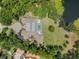 Aerial view of a luxury home with a private pool, manicured lawn, and bordered by lush trees and a serene lake at 1112 Preserve Point Dr, Winter Park, FL 32789