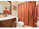 Bathroom with wood vanity, framed mirror, red shower curtain and red towels at 11602 Graces Way, Clermont, FL 34711