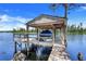 Dock featuring a boat lift and covered shelter with views of the lake at 11602 Graces Way, Clermont, FL 34711