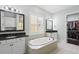 Well-lit bathroom with dual sinks, granite countertops, a soaking tub, and access to a walk-in closet at 1365 Tappie Toorie Cir, Lake Mary, FL 32746