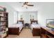 Bright bedroom features two beds, a ceiling fan, and a bookshelf with natural light from two windows at 1365 Tappie Toorie Cir, Lake Mary, FL 32746