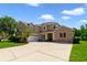 Two-story home with a three car garage, brick accent wall, and manicured landscaping at 1425 Riviera Dr, Kissimmee, FL 34744