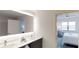 Elegant bathroom featuring double sinks, a large mirror with modern lighting, and a view into the bedroom at 14501 Grove Resort Ave # 2440, Winter Garden, FL 34787