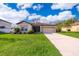 Charming single-story home boasts a lush green lawn and inviting curb appeal with a two car garage and neutral color palette at 16379 Blooming Cherry Dr, Groveland, FL 34736