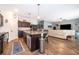 Open kitchen featuring granite counters, a spacious island, dark wood cabinets, and stainless steel appliances at 16379 Blooming Cherry Dr, Groveland, FL 34736