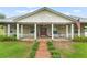 Welcoming front porch with white railing and rocking chairs leads to a home with beautiful landscaping and metal roof at 17523 Doris St, Montverde, FL 34756