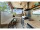 Functional outdoor kitchen with stainless steel appliances, bar seating, and tropical accents at 17523 Doris St, Montverde, FL 34756