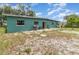 The back of a home featuring a small patio and a yard with scattered vegetation at 240 W Grossenbacher Dr, Apopka, FL 32712