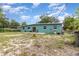 Exterior view of the rear of a house with a small patio area and a partially overgrown yard at 240 W Grossenbacher Dr, Apopka, FL 32712