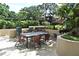 Outdoor kitchen area with multiple grills, dining table, and seating surrounded by lush landscaping at 2928 Lake Pineloch Blvd # Ge, Orlando, FL 32806