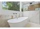 Bright bathroom featuring a modern soaking tub with marble accents and a large window showcasing greenery at 388 Hampton Hills Ct, Debary, FL 32713