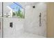 Modern bathroom features marble tile, rain shower head, and skylight with a view of the blue sky and trees at 388 Hampton Hills Ct, Debary, FL 32713