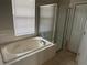 Bathroom showcasing a soaking tub and glass-enclosed shower with tile surround at 4034 Bougainvillea Pl, Kissimmee, FL 34746