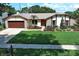 Inviting home featuring stone detailing, a manicured lawn, mature landscaping, and an attached two-car garage at 414 Bonifay Ave, Orlando, FL 32825