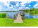 A dock extends onto a pond with a covered seating area and signage in a grassy area under a partly cloudy sky at 489 Meadowood Blvd, Fern Park, FL 32730